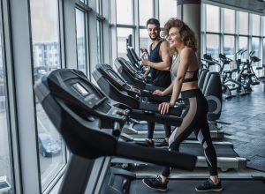 Portrait of young sports couple making cardio workout in modern gym.